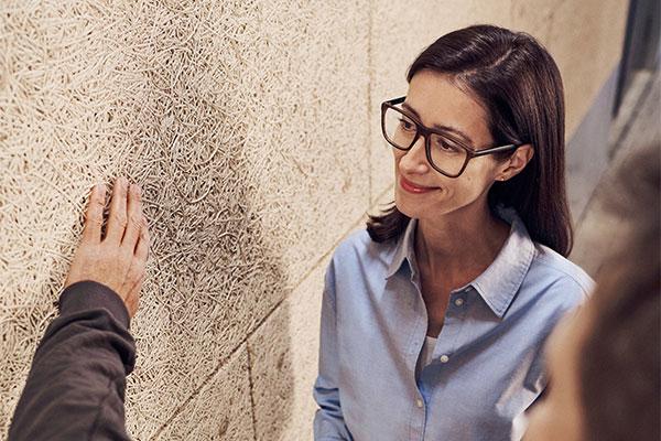 An architect and a craftsman inspect a wall clad with Heraklith wood wool panels